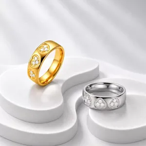 Nahaufnahme von gold- und silbernen Edelstahlringen mit herzförmigem Diamantbesatz.