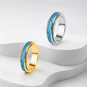 Close-up detail of blue opal inlay on silver and gold stainless steel spinner rings