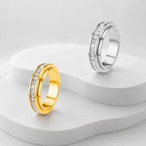 Nahaufnahme von goldenen und silbernen Spinner-Ringen mit Zirkonia auf weissem Podest