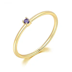 Primer plano de un anillo minimalista chapado en oro con una piedra de circón púrpura