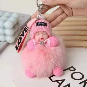 Primer plano detallado del llavero de muñeca dormida con pompón rosa y gorro.
