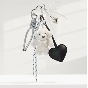 Plush bear keychain with pearl bow and black heart charm, cute bag pendant and accessory detail.