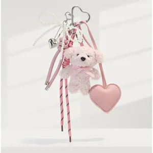 Detailed view of fluffy pink teddy bear keychain featuring lovely pearl bow and heart charm.