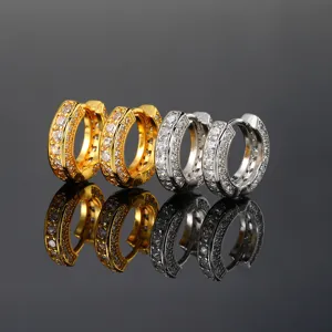 Closeup of sparkling pave zircon huggie hoop earrings in gold and silver, detailed texture.