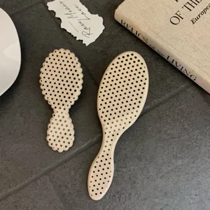 Close-up detail of beige boar bristle hairbrushes with stylish black polka dot patterns