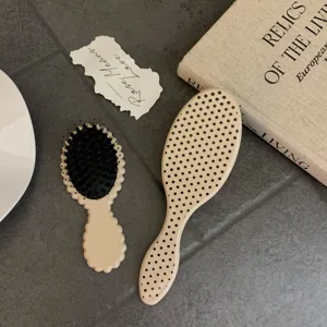 Detailed view of two boar bristle massage hairbrushes with stylish polka dots and wavy handles