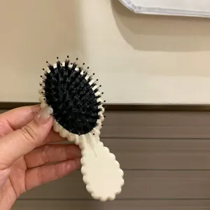 Close-up view of a boar bristle hairbrush with a cream wavy handle for scalp massage