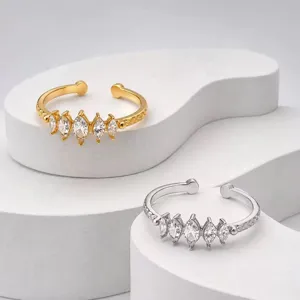 Elegante Nahaufnahme von Ringen mit Marquise-Steinen in Gold und Silber auf weißer Bühne.