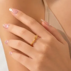 Nahaufnahme eines vergoldeten, gedrehten Rings aus Edelstahl an einem Finger.
