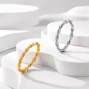 Minimalistische gedrehte Ringe aus Edelstahl in Gold und Silber auf weißen Podesten
