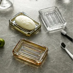 Detailed view of luxury glass soap dishes in amber and clear finishes on marble.
