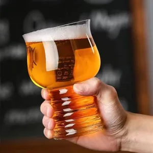 Primer plano de una mano sosteniendo un vaso de cerveza artesanal con espuma blanca.