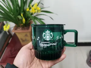 Dark green transparent glass coffee mug with Starbucks logo, lid and convenient handle.