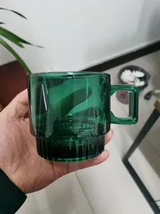 Close-up view showing the retro dark green glass coffee cup, highlighting the ribbed base design.