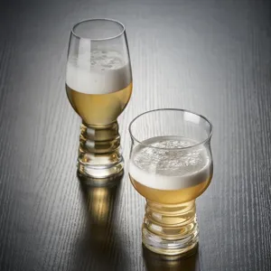 Vista detallada de vasos de cerveza artesanal con bases nervadas sobre madera oscura.