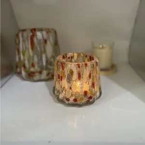 Close-up of handmade crackle glass candle holder with colorful spots, warm and artistic.