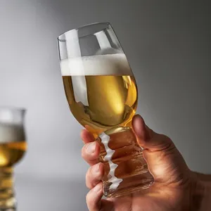 Mano sosteniendo un vaso de cerveza artesanal creativo con tallo estriado