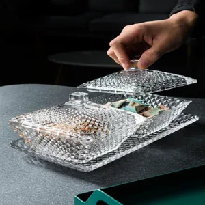 Nahaufnahme einer Hand, die den Deckel einer dekorativen Glas-Bonbondose mit Rautenmuster hebt