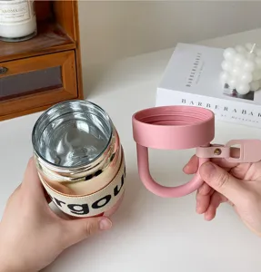 Dettaglio di una tazza in vetro rosa sfumato con coperchio a maniglia e cinturino