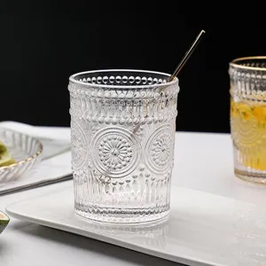 Close-up of a vintage embossed glass cup with sunflower pattern on a white tray