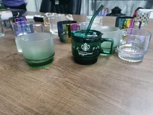 Glass coffee mug with straw and lid, stylish desktop display of drinkware and cups.
