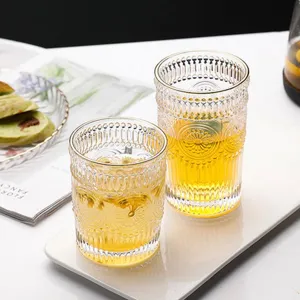 Close-up of vintage embossed glass cups with gold rims and sunflower patterns.