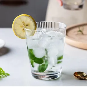 Detailed view of a ribbed glass cup filled with ice, mint, and a lemon slice.