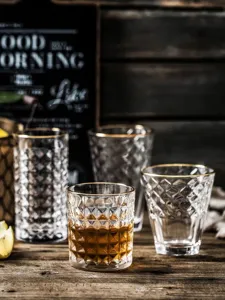 Detail view of retro relief glass cups with gold rim on a rustic wooden table