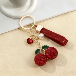 Primo piano del portachiavi a ciliegia in strass rosso lucido con finiture metalliche.