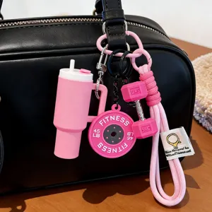 Close-up of pink fitness-themed bag charms with mini tumbler and dumbbell details