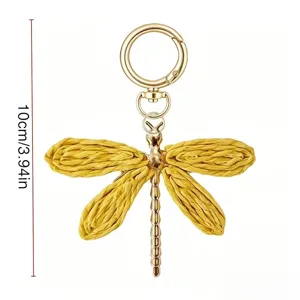 Portachiavi a libellula in paglia intrecciata a mano, minuteria metallica dorata.