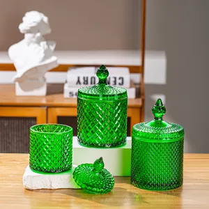 Set di barattoli in vetro verde smeraldo con coperchi decorativi su tavolo di legno