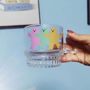 Clear glass coffee mug with cute colorful bears pattern and comfortable handle detail shot.