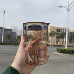 Mano che tiene una tazza da caffè impilabile in vetro ambrato resistente