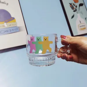 Clear glass coffee mug with cute colored cartoon bears pattern, transparent handle style.