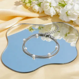 Elegantes mehrlagiges Edelstahlarmband mit Perlen auf einer Spiegeloberfläche