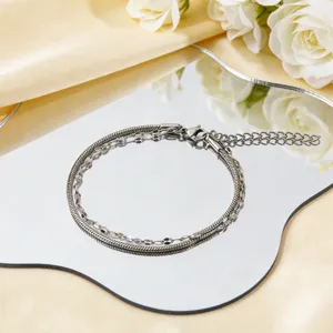 Minimalistisches mehrlagiges Armband aus silbernem Edelstahl auf einem Spiegel mit Rosen