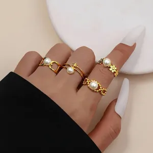 Detailansicht von vier minimalistischen goldenen Titanstahlringen mit Perlenakzenten