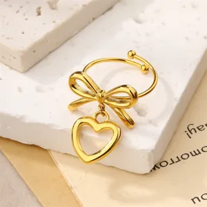 Detailed view of an 18k gold plated open ring featuring a bow and hollow heart charm.