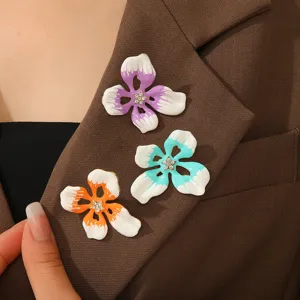 Detail von drei bunten Emaille-Blumenbroschen an einem braunen Anzugrevers.