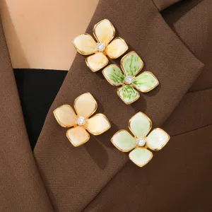 Nahaufnahme von vier eleganten Emaille-Blumenbroschen an einem braunen Jackenkragen