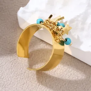 Breiter goldener Edelstahlring mit blauen Natursteinperlen und kleinen Sternanhängern