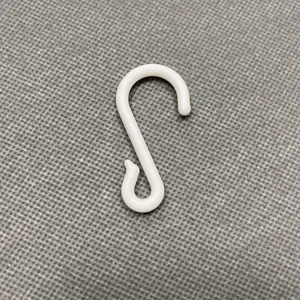 White plastic S-hook for shelf display and snack hanging on textured grey background.