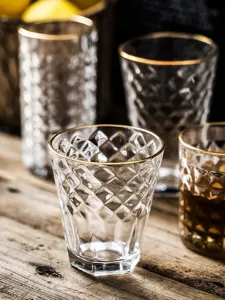 Close-up detail of a vintage relief glass cup featuring a luxury gold rim and diamond texture