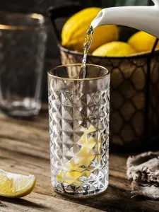 Close-up of retro embossed glass cup with gold rim being filled with fresh water