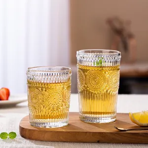 Elegant vintage embossed sunflower glass cups for juice or tea served on a wooden board.