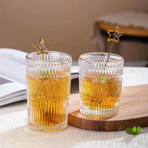 Vintage embossed glass cups with gold rims, sunflower patterns, and star stirrers