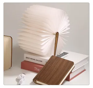 Dettaglio di una lampada a libro pieghevole in legno in posizione aperta e chiusa su tavolo