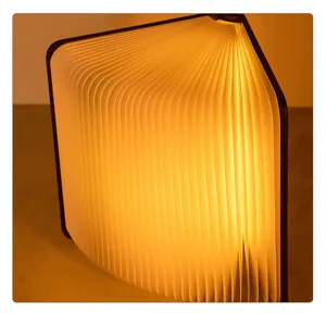 Dettaglio di una lampada a libro pieghevole accesa con calda luce LED e pagine a ventaglio