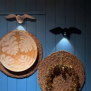 Modern black and white seagull-shaped motion sensor LED wall lamps on blue wall